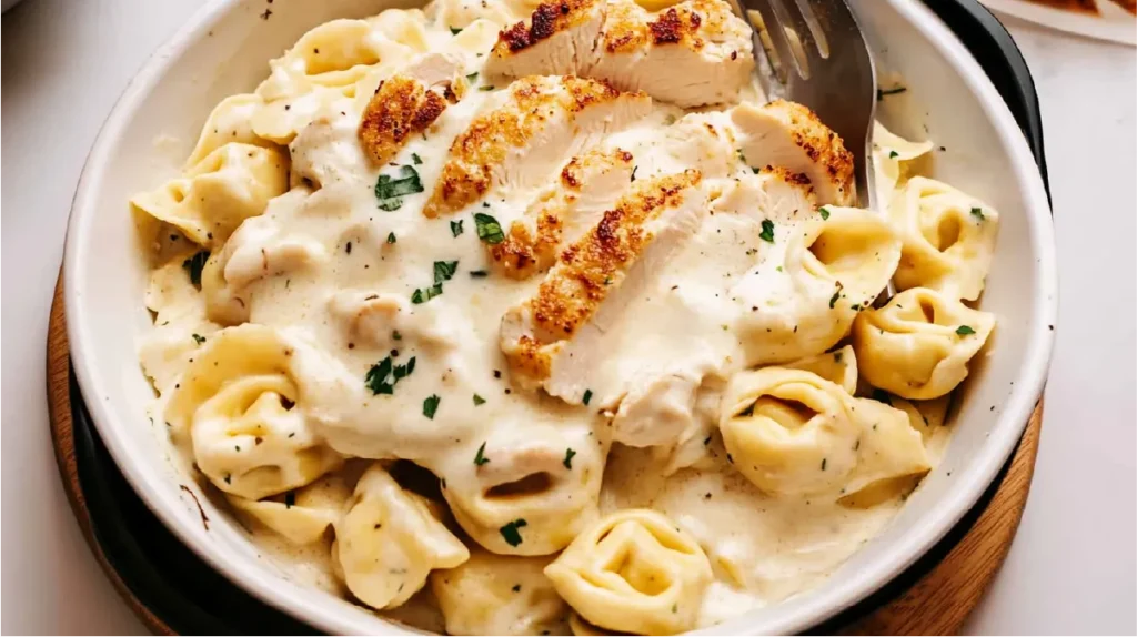 A bowl of Chicken Tortellini Alfredo Olive Garden style with grilled chicken and creamy Alfredo sauce.